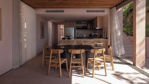 A modern kitchen with wooden cabinets, a central island, and a dining area with wooden chairs.