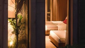 A multi-level hotel room with a balcony, a bed, and a small seating area.