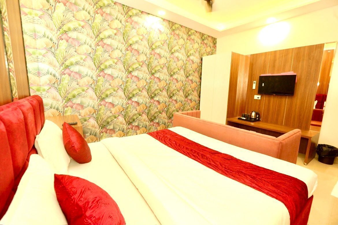 Hotelkamer met een bed, een televisie, een bureau en een muur met een bladerpatroon.