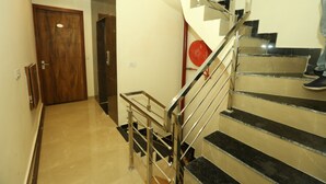 A staircase with metal railings and black steps, leading to a landing with a wooden door. - Om B & B (Amritsar)
