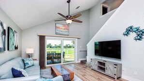 A modern living room with a sofa, coffee table, TV, and a ceiling fan.