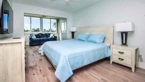 A bedroom with a bed, nightstands, a TV, and a ceiling fan.