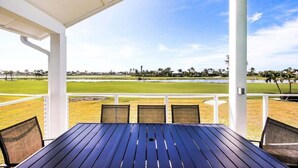 A covered outdoor seating area with a view of a golf course.