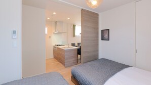 A modern bedroom with two beds, a kitchenette, and a bathroom. - Everynet Shinjuku II by Tranova (Tokyo)