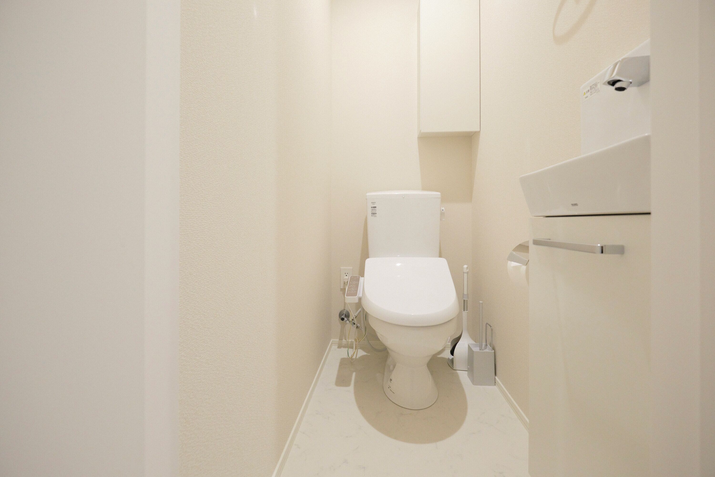 A small, modern bathroom with a toilet, a hand dryer, and a towel rack.