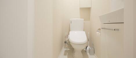A small, modern bathroom with a toilet, a hand dryer, and a towel rack.