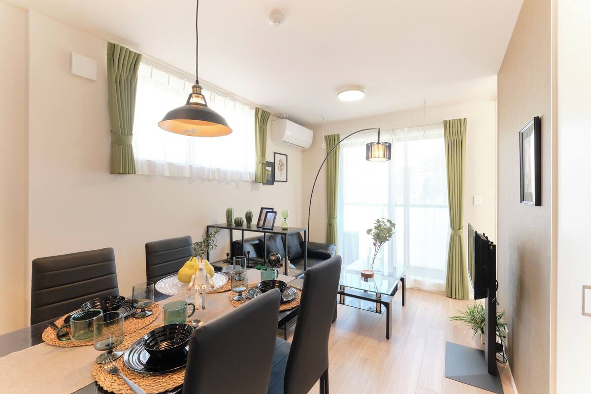 Una sala de estar moderna con comedor, que incluye un sofá, una mesa de centro y un televisor montado en la pared.