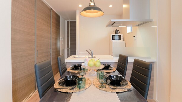 A dining area with a table set for four, a modern pendant light, and a kitchen in the background. - Everynet Shinjuku II by Tranova (Tokyo)