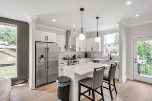 A modern kitchen with white cabinets, stainless steel appliances, and a central island with bar stools.