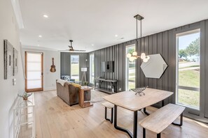 Cozinha moderna com área de refeições, janelas amplas e televisão integrada.