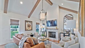 A spacious living room with a fireplace, leather sofa, and a television mounted on the wall. - 32 Acre Farm at Maven Stables ｜Spring Hill (Columbia)