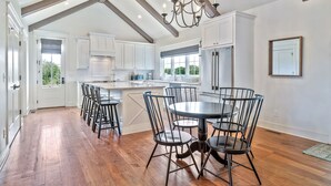 A spacious kitchen with white cabinets, a large island, and a dining area with metal chairs. - 32 Acre Farm at Maven Stables ｜Spring Hill (Columbia)