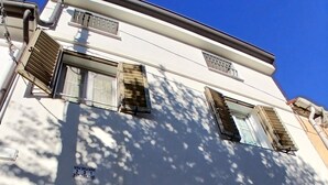 A white building with a door and windows, including a window with a metal grille. - Romantic Eco-Lodge in the Heart of Trieste (Trieste)