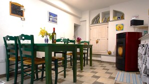 A dining area with a table and chairs, a refrigerator, and a wall with a picture and a sign. - Romantic Eco-Lodge in the Heart of Trieste (Trieste)