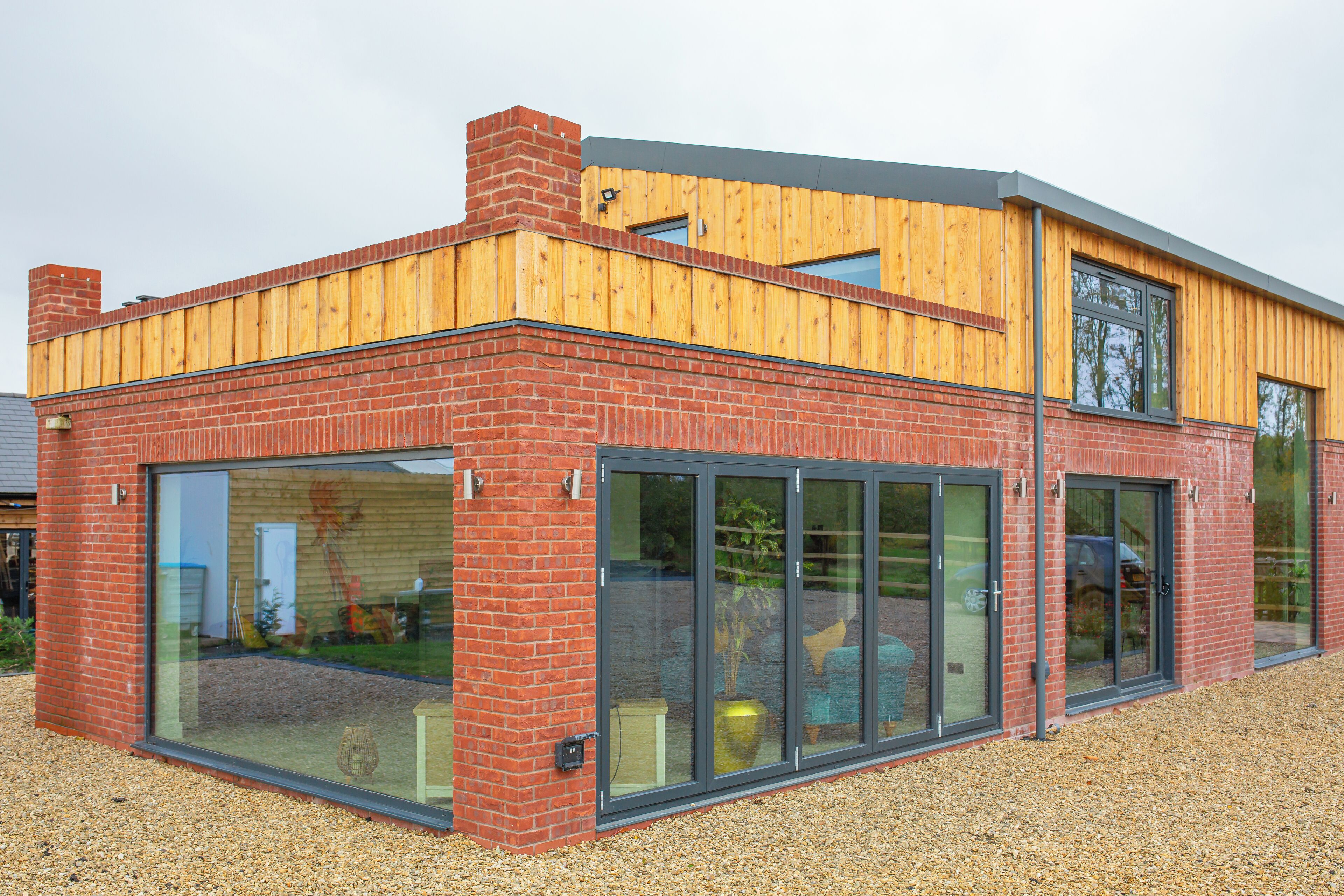 A modern two-story building with a brick facade, large glass windows, and a wooden upper floor.