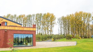 A modern house with a brick exterior, large glass windows, and a wooden roof. - Orchard Barn-Luxury 4 BD Barn Conversion (Pershore)