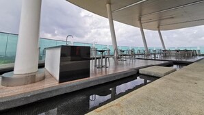 A rooftop terrace with a pool, seating area, and a glass balustrade. - City View Southkey 2BR2FREE 18F By Natol (Johor Bahru)