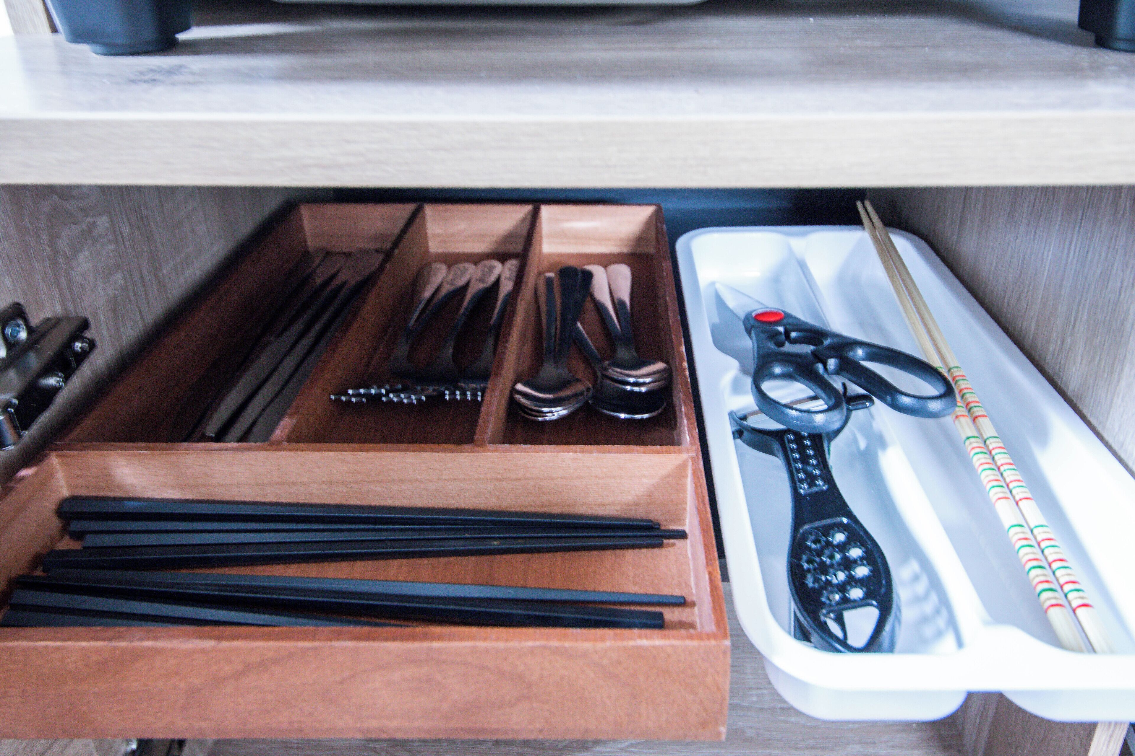 A drawer with chopsticks, scissors, and a remote control.