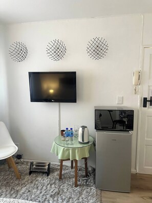 Cozy living space with a flat-screen TV, compact kitchenette, and comfortable seating area.