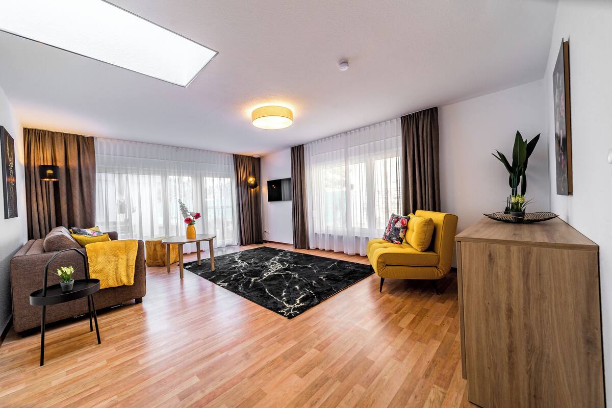 A modern living room with a sofa, yellow armchair, and a wooden sideboard.