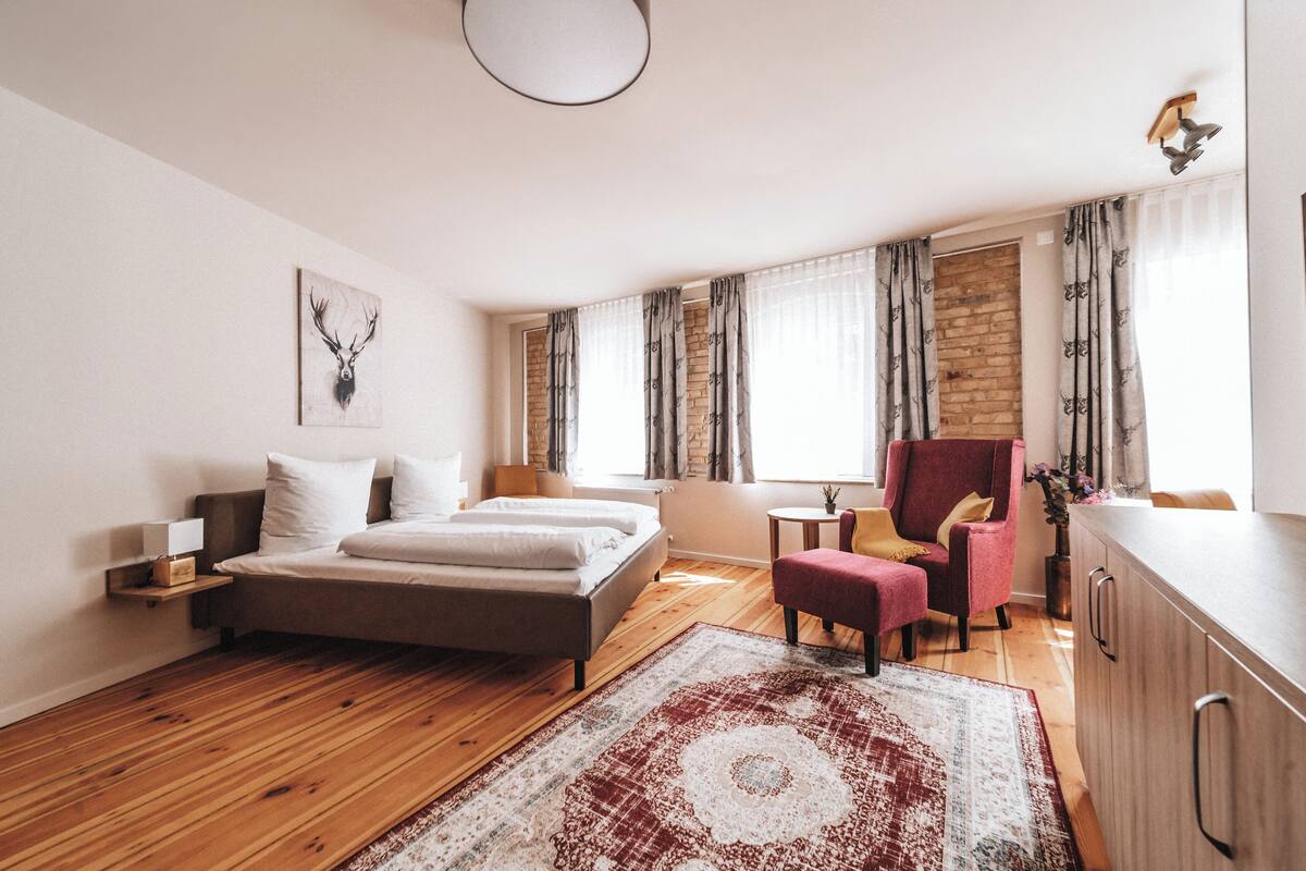 A modern bedroom with a bed, a chair, a small table, and a cabinet.