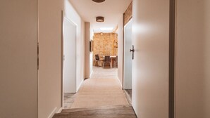 A hallway leading to a dining area with a brick wall and wooden furniture. - Fontane Apartments (Schorfheide)