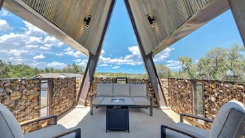 Relax on the patio with a sofa, chairs, and a small table, surrounded by a metal fence and stone wall.