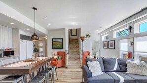 Una cocina moderna con comedor, una escalera y una sala de estar con sofá.