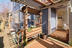 Una pergola in legno con un fioriere, una scala di legno e una porta con pentole appese.