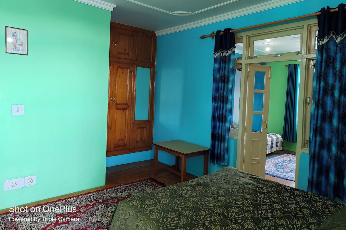 Una camera da letto con un letto, un armadio in legno, un tavolino e uno specchio.