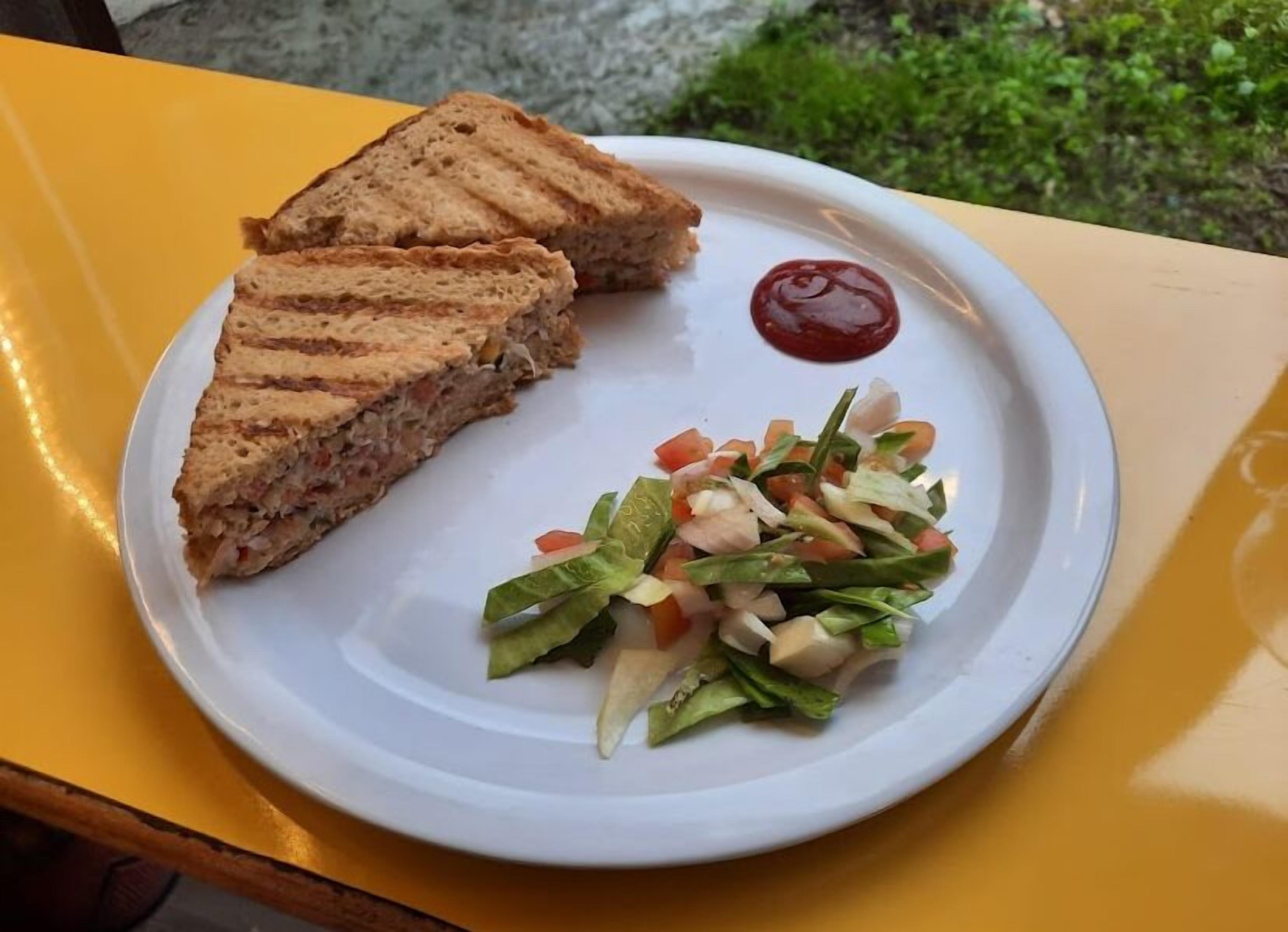 A plate with a sandwich and a side salad on a yellow table.