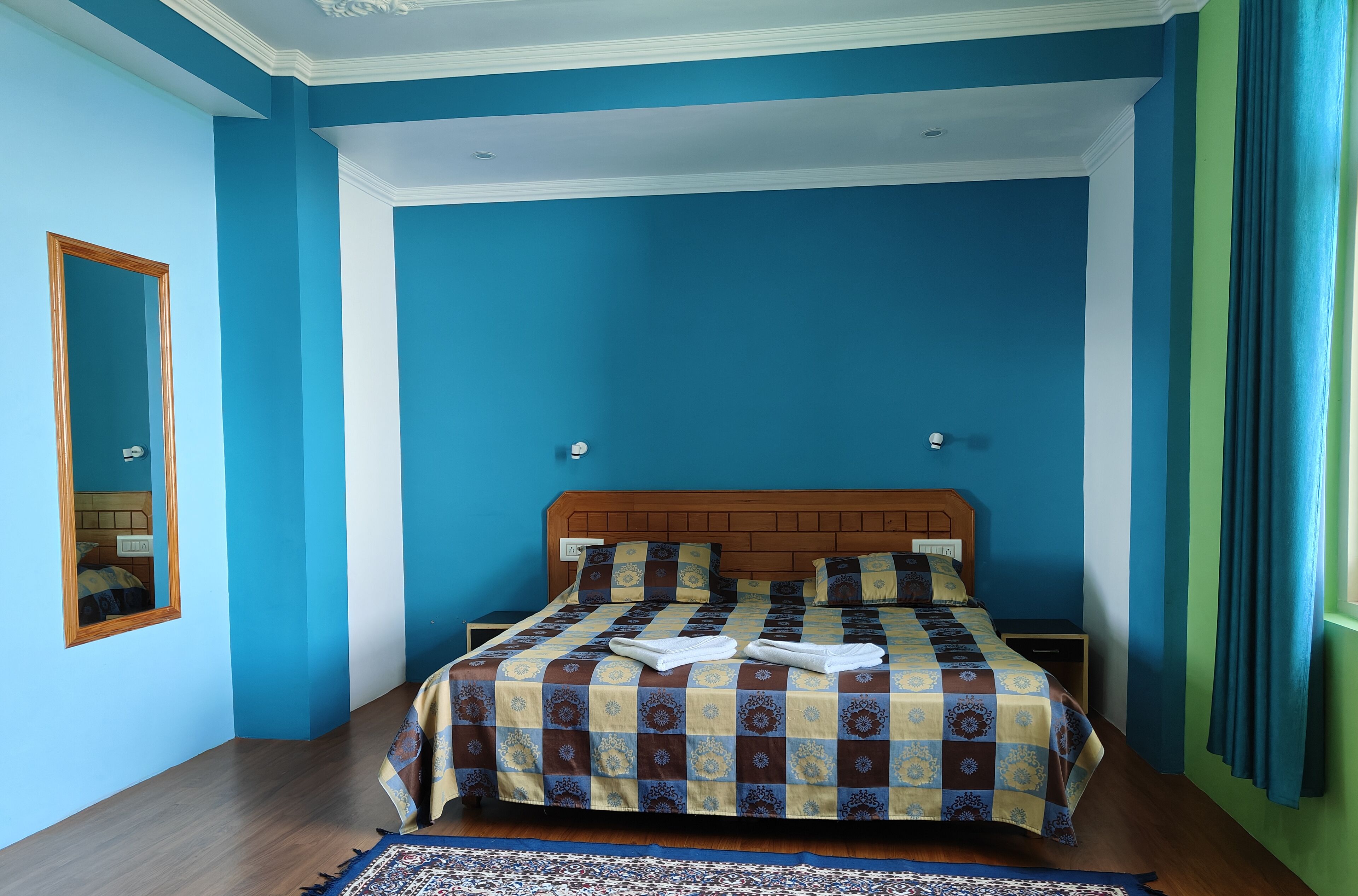 A bedroom with a large bed, a wooden headboard, a mirror, and a nightstand.