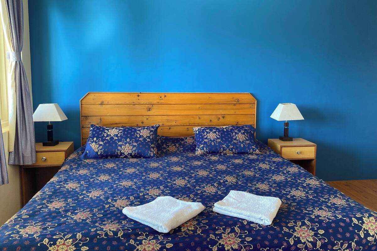 Un letto con copriletto floreale, due cuscini e due comodini con lampade.
