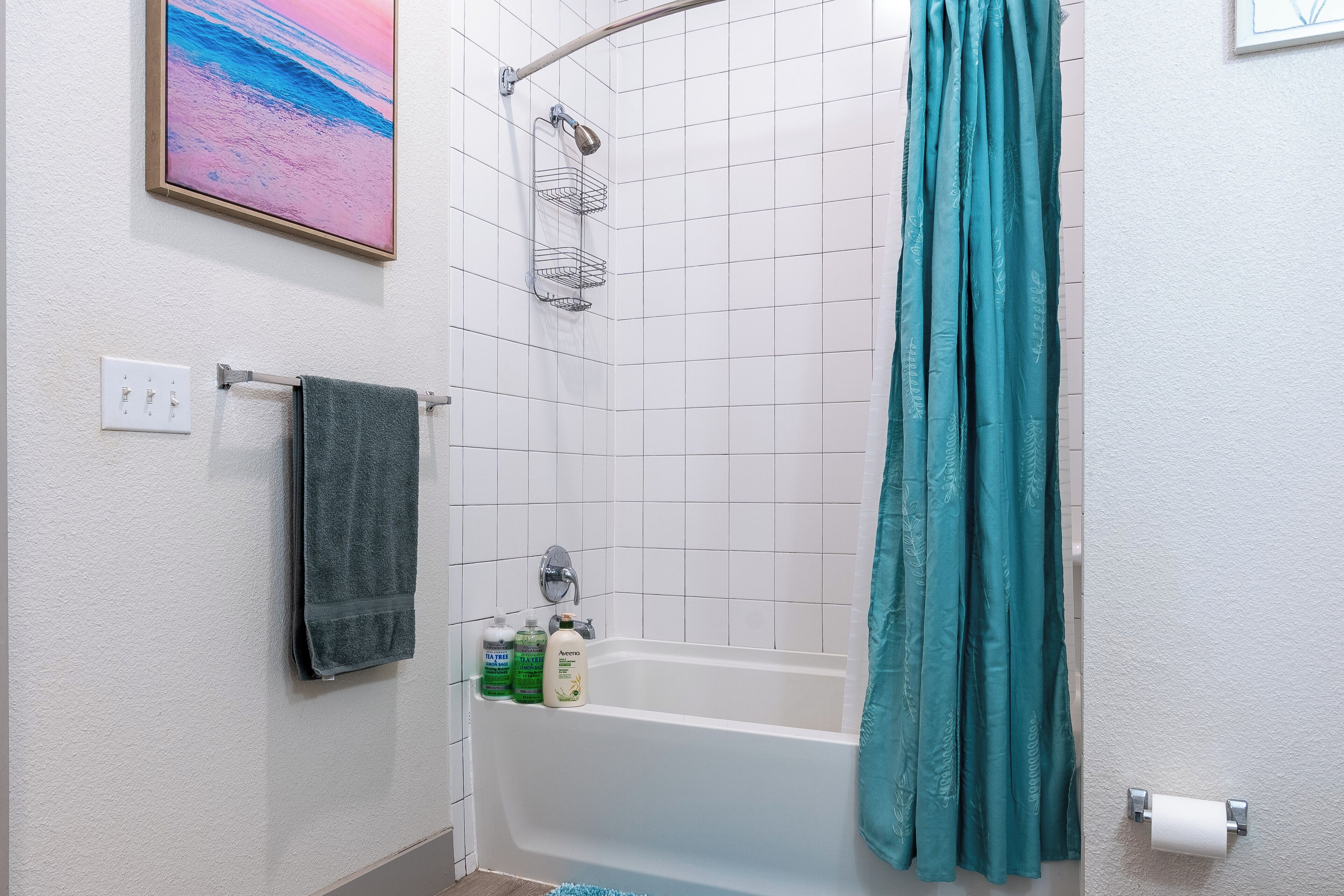 A bathroom with a bathtub, a towel rack, a shower curtain, and a toilet paper holder.