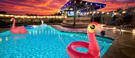 A swimming pool with inflatable flamingos and a covered area with string lights.