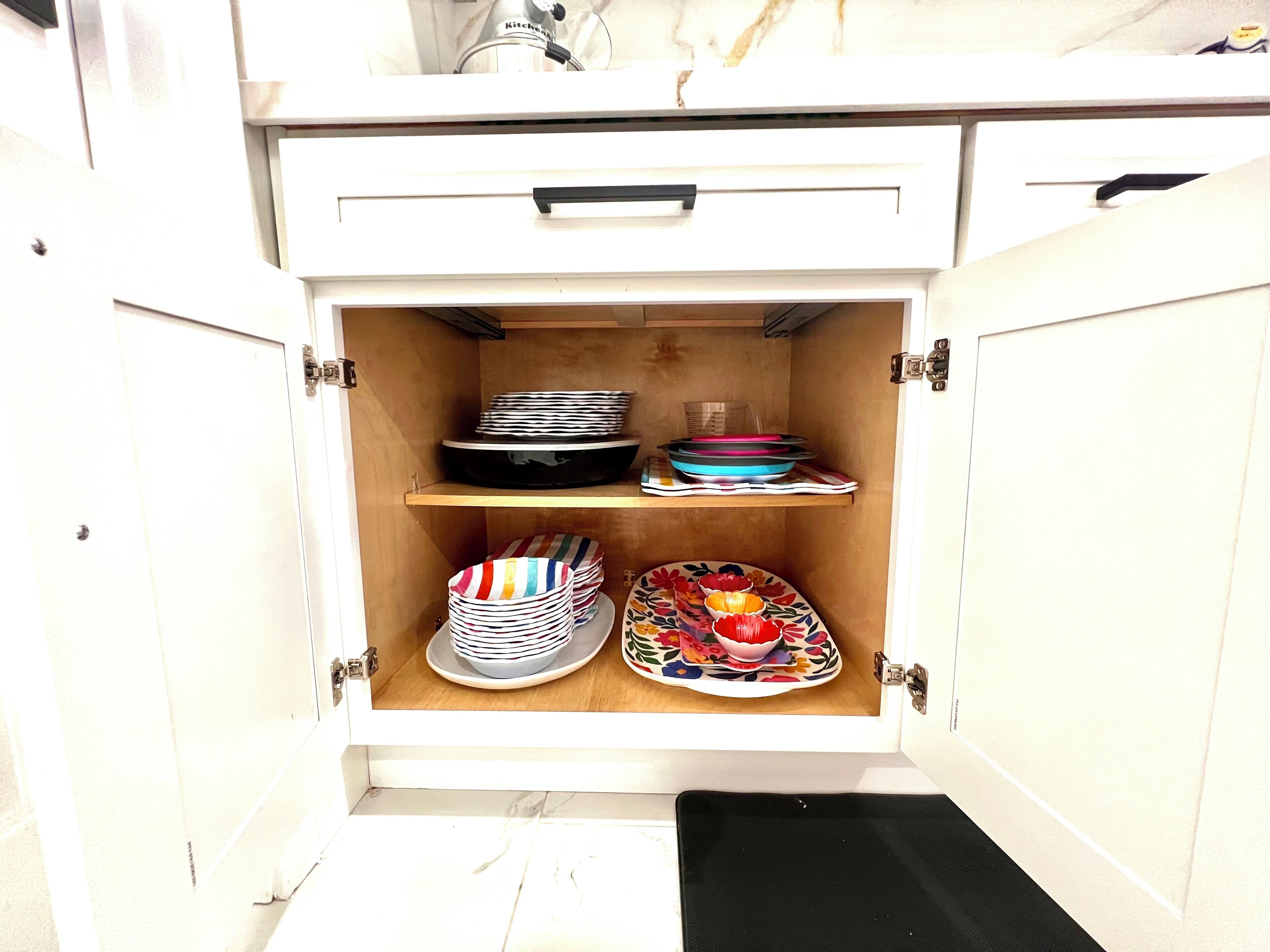Ein Küchenschrank mit Regalen, auf denen Teller, Schüsseln und ein Schneidebrett liegen.