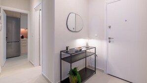 A modern kitchen with a built-in refrigerator, a dining area with a table and chairs, and a white door. - Lycabettus Modern Retreat (Athina)