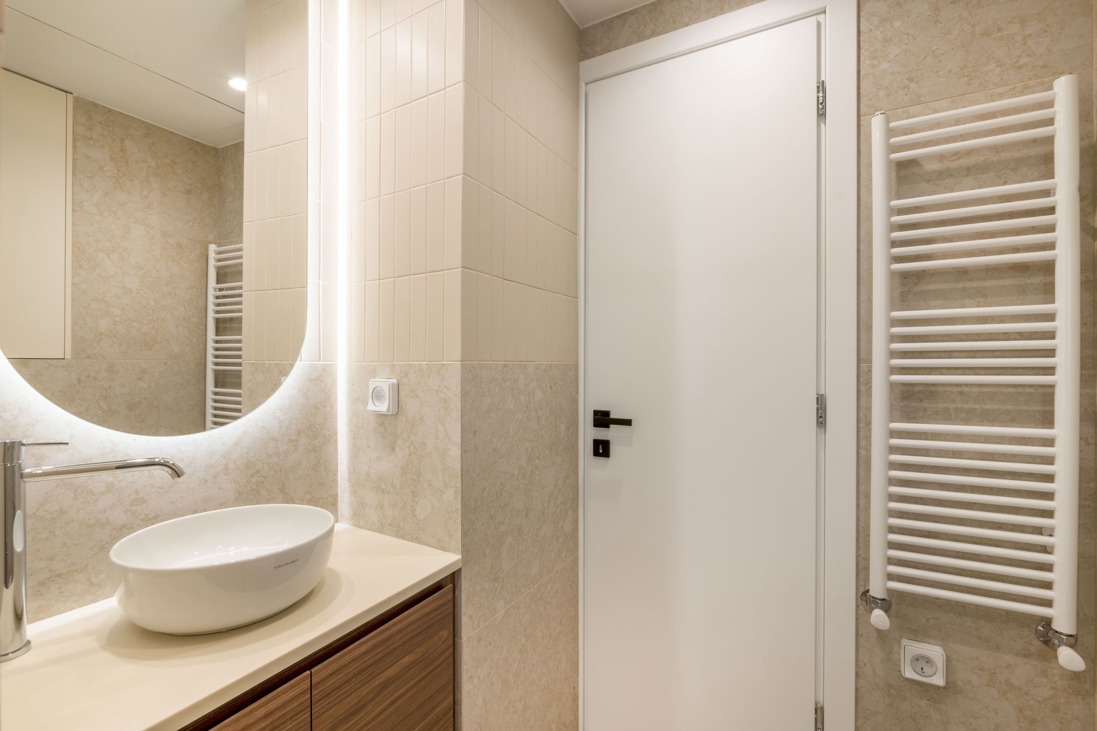 A modern bathroom with a white sink, a mirror, and a towel rack.