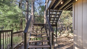 A wooden staircase with metal railings leading to a covered area surrounded by trees. - Xbox*Ping Pong* Pop-a-shot*Game Room* (Flagstaff)