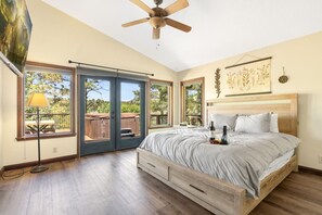 A bedroom with a bed, a ceiling fan, and a view of the outdoors.