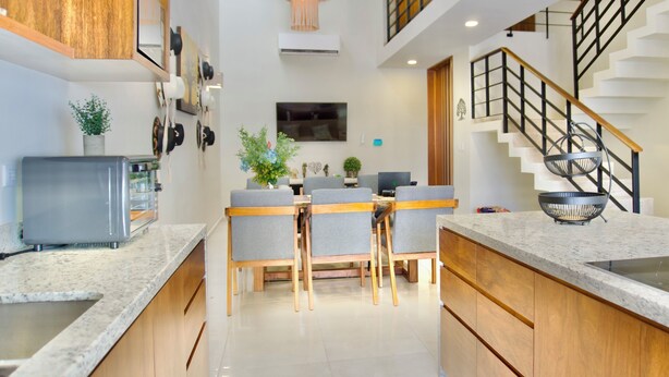 Una cocina moderna con encimeras de granito, armarios de madera y una isla central con asientos.