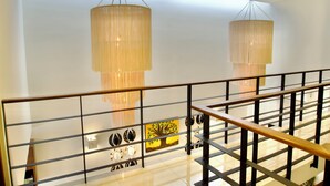 Un interior moderno con una escalera, barandillas metálicas y arte decorativo en las paredes, incluyendo un cuadro de un árbol.