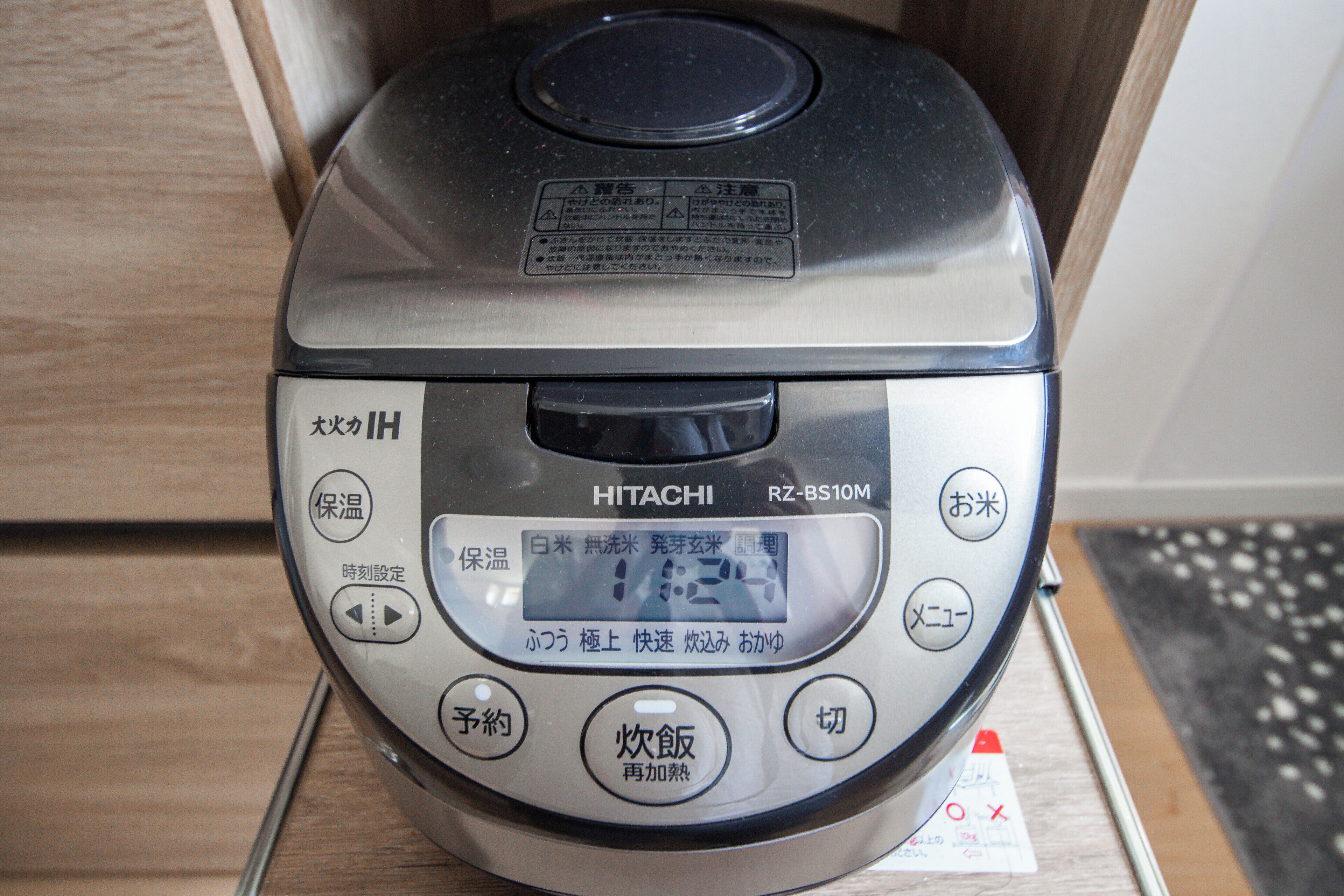 Cocina d'arròs HITACHI amb pantalla digital, botons per a diverses funcions i text en japonès.