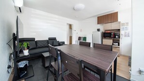 A modern kitchen with a dining area, a sofa, and a small table. - Apollo (Hakodate)