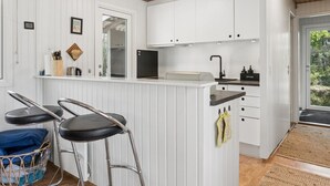 Une cuisine moderne avec des meubles blancs, un comptoir noir et un tabouret de bar.