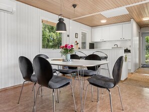 A modern kitchen with white cabinetry, a round dining table with black chairs, and a pendant light.