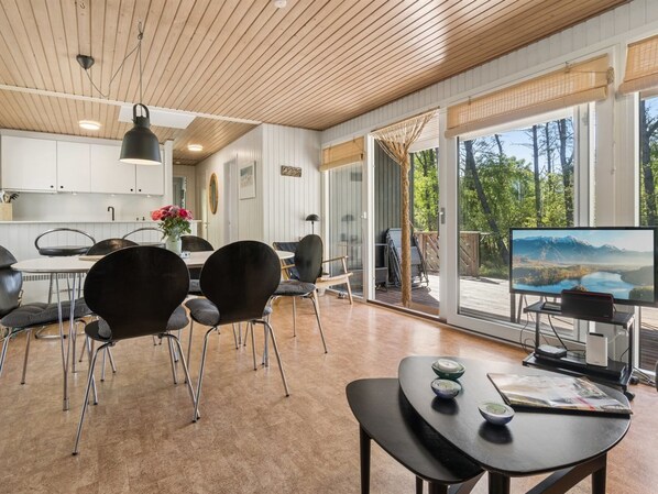 A modern interior with a dining area, kitchen, and a large sliding glass door leading to an outdoor deck.