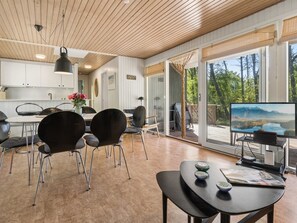 A modern interior with a dining area, kitchen, and a large sliding glass door leading to an outdoor deck.