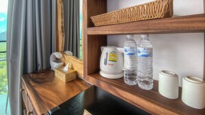 Uno scaffale di legno con un dispenser di fazzoletti, un bollitore elettrico bianco e due bottiglie d'acqua.