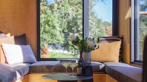 A cozy seating area with a view of greenery outside, a small table with a vase and a book titled "FLAVOURS OF VICTORIA".